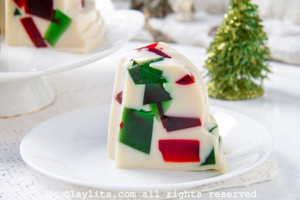 Side view of a slice of red and green mosaic jello on a plate to see the cubed design.