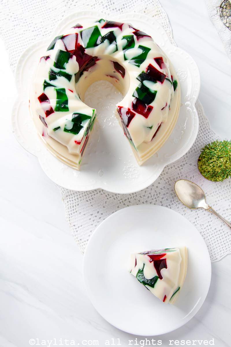 Overhead shot of the Christmas jello on a cake stand with a slice on a plate next to it.