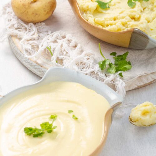 Two serving bowls of different styles of mashed potatoes garnished with parsley.