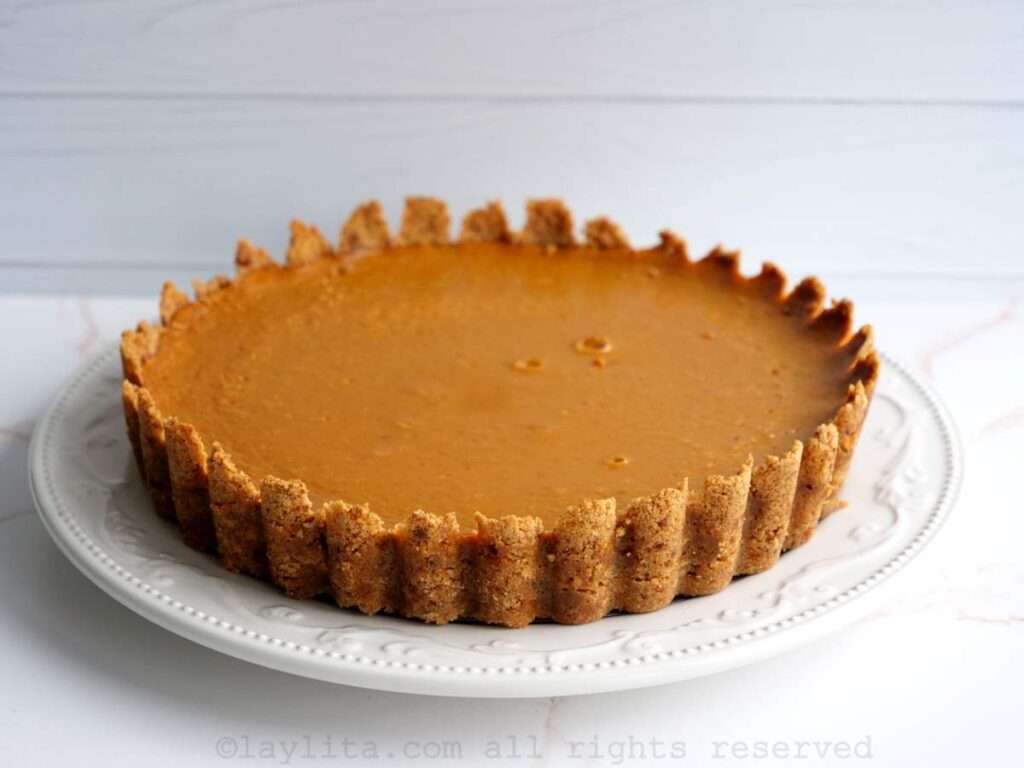 Pumpkin pie after baking placed on a white serving dish.