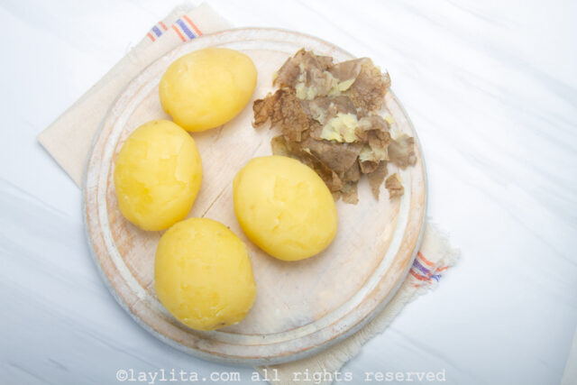 Four peeled cooked potatoes on a board
