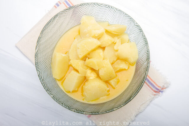 Cooked potato pieces with melted butter in a bowl