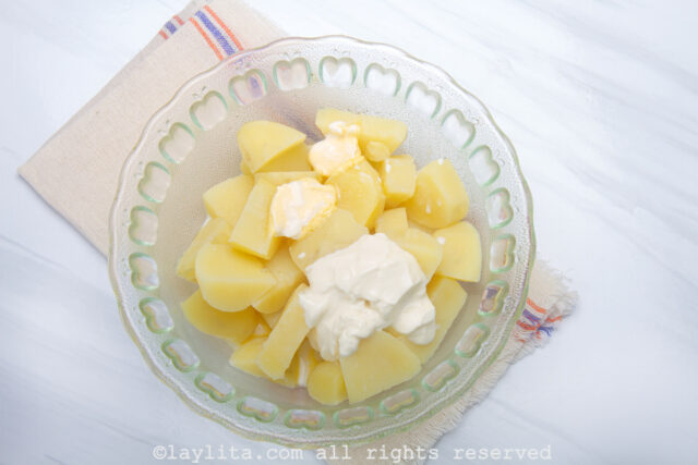 Cooked potatoes, cream cheese and butter in a glass bowl