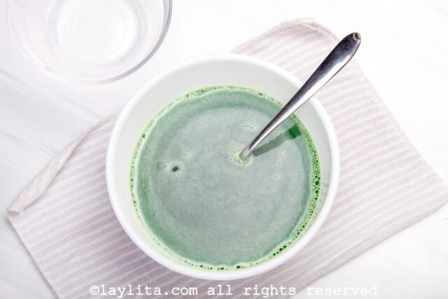 Green jello being mixed in white bowl