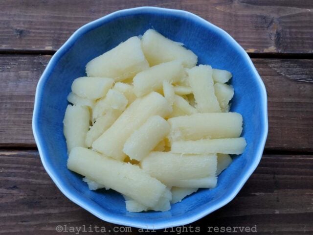 A blue bowl filled with pieces of cooked cassava