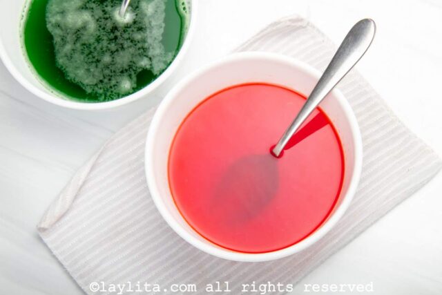 Red jello being mixed in white bowl
