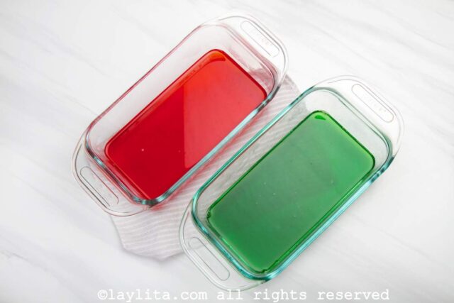 Green and red jello in rectangular glass containers on a white countertop