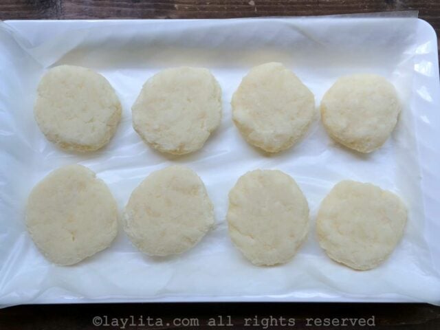 Eight uncooked yuca patties on a white platter