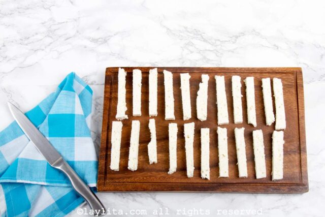 A cutting board with several pieces of cheese cut into strips