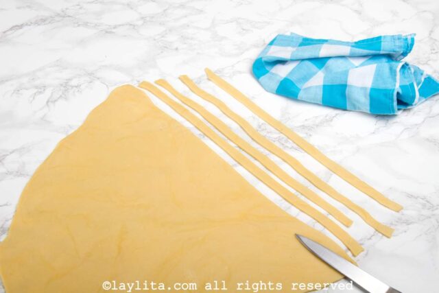 A sheet of dough being cut into long strips