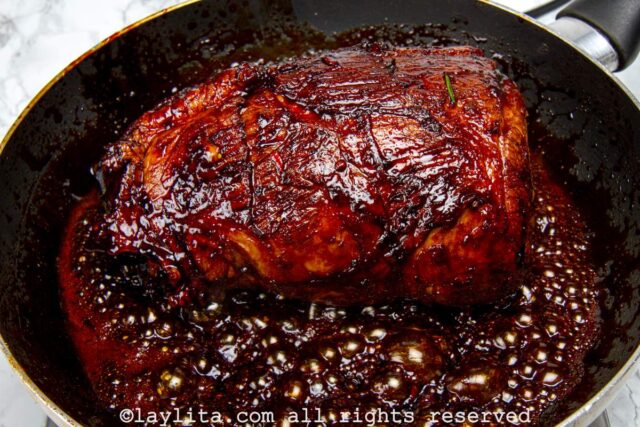 Beef roast being seared in the dark sugar in a pan.