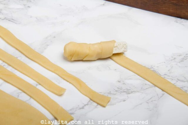 Wrapping dough around a cheese stick to make tequeños