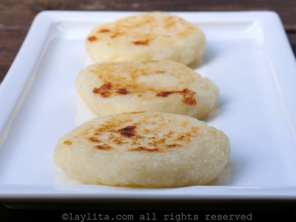 Three tortillas de yuca or cassava patties lined up on a white plate.