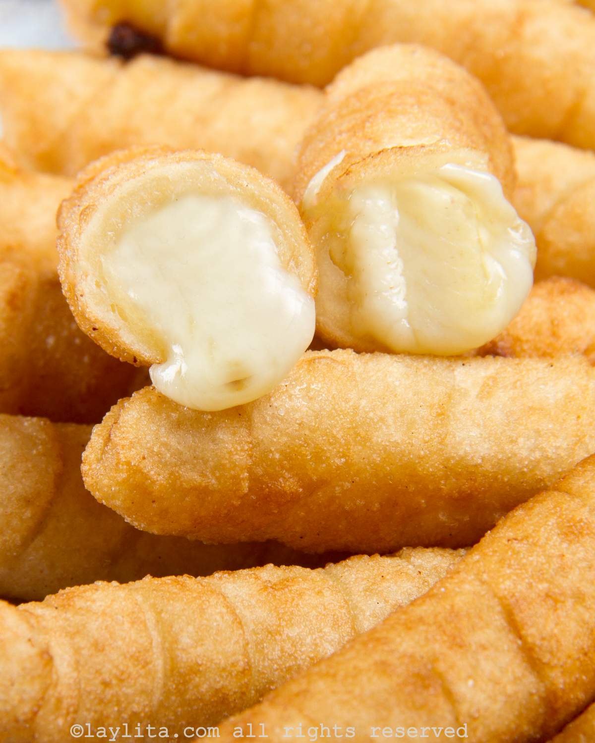 Close up shot of a Venezuelan tequeño broken in half to show the gooey, cheesy center.