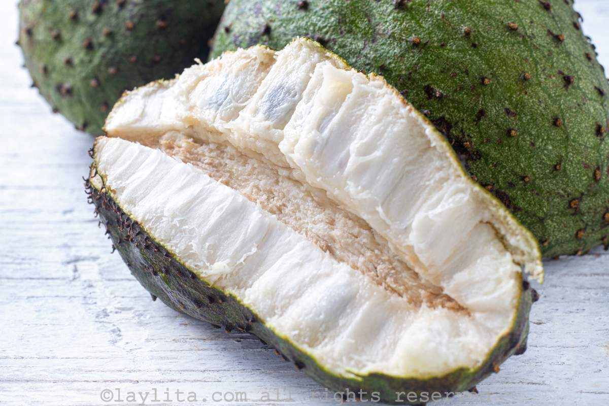 Guanabana or soursop fruit cut in half to show the pulp with a additional whole ones in the back