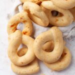 Ring shaped Paraguayan chipa breads in a basket lined with linen overflowing out of the baskets.