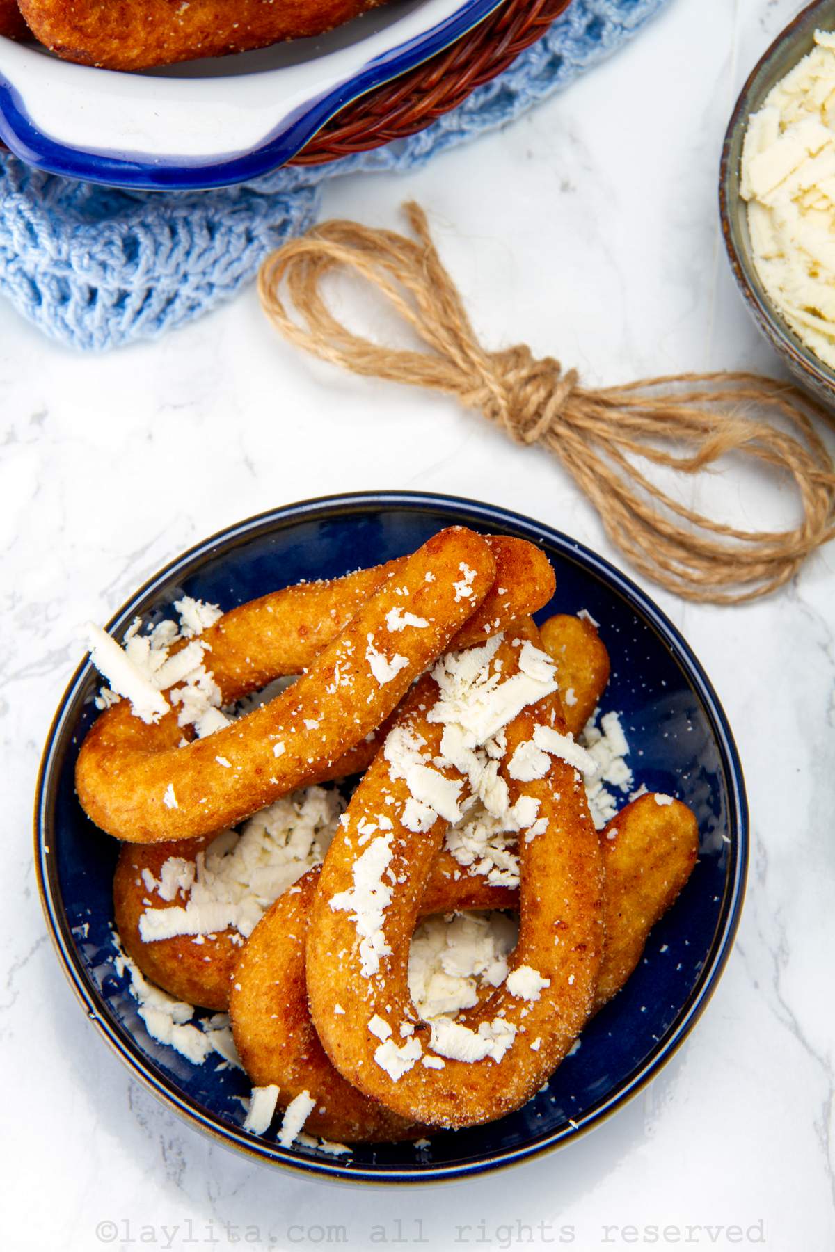 Overhead shot of mandocas in a blue bowl topped with grated cheese.