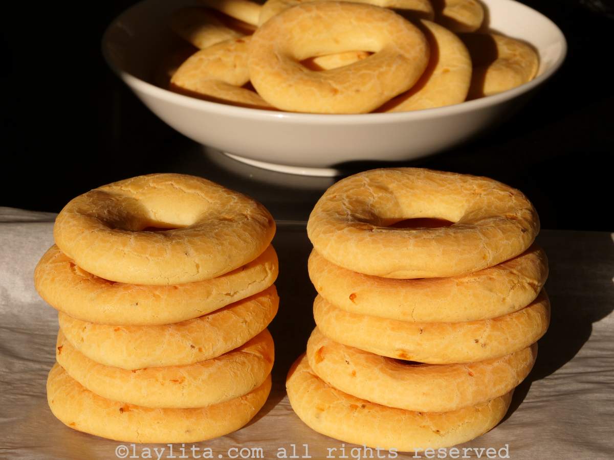 Chipa stacked on top of each other and some with a bowl with a black background behind it and shadows from the sun