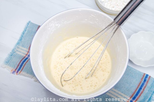A liquid mix and a whisk in a mixing bowl