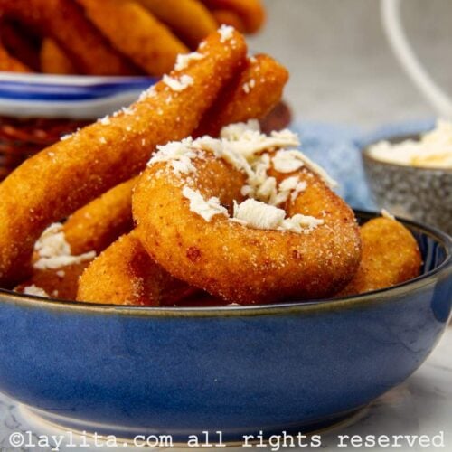 Side view of fried mandocas in a bowl with grated white cheese on top