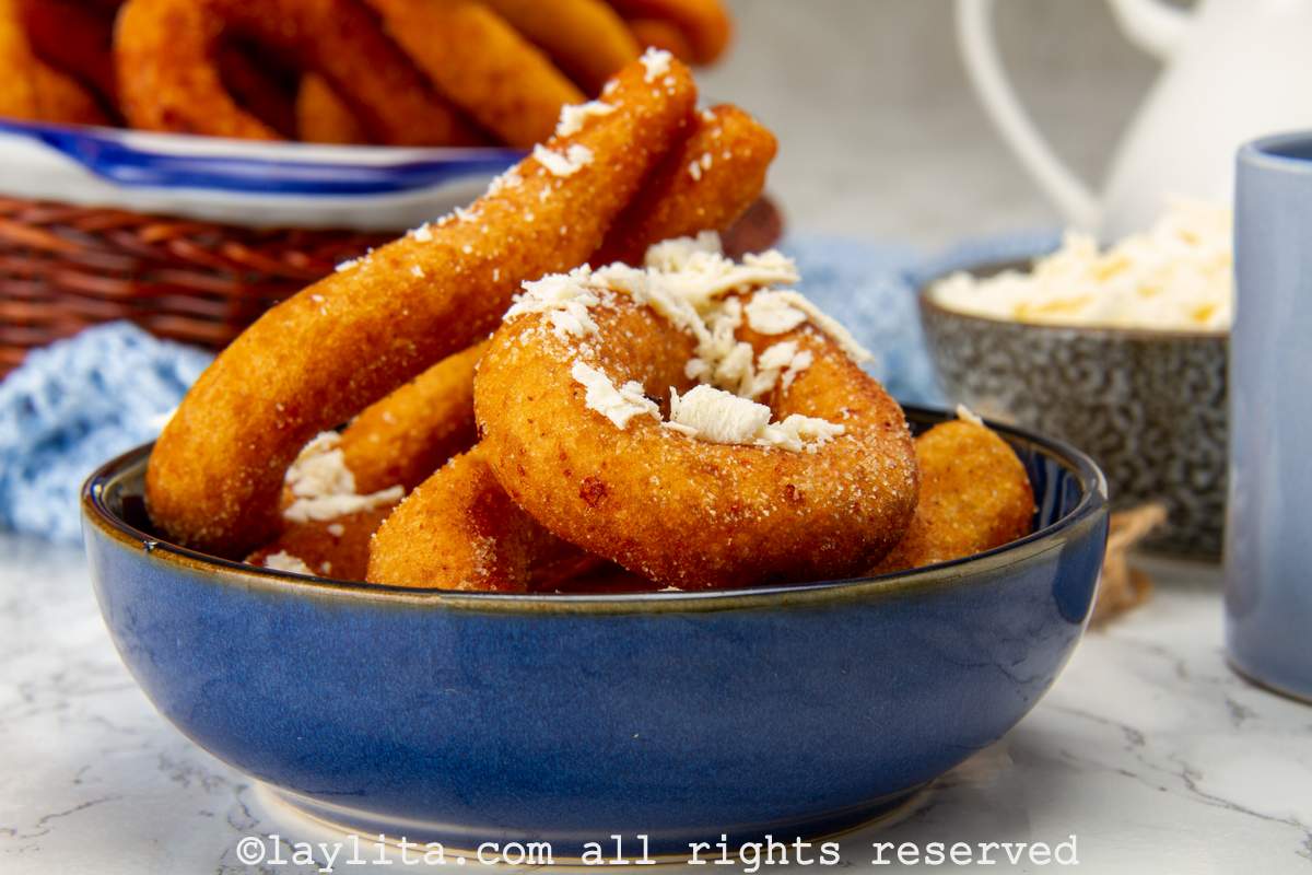Side view of fried mandocas in a bowl with grated white cheese on top