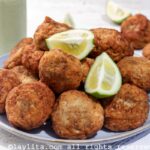 Salt cod fritters on a plate with lime wedges on top