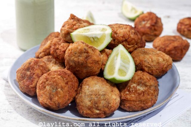 Salt cod fritters on a plate with lime wedges on top