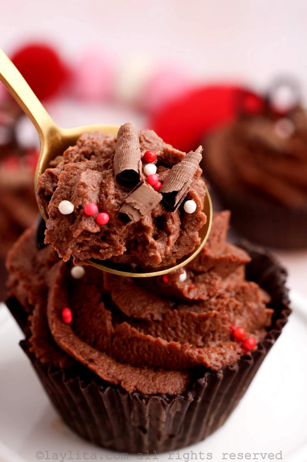Closeup of a spoon full of chocolate mousse with a chocolate mousse cup in the background