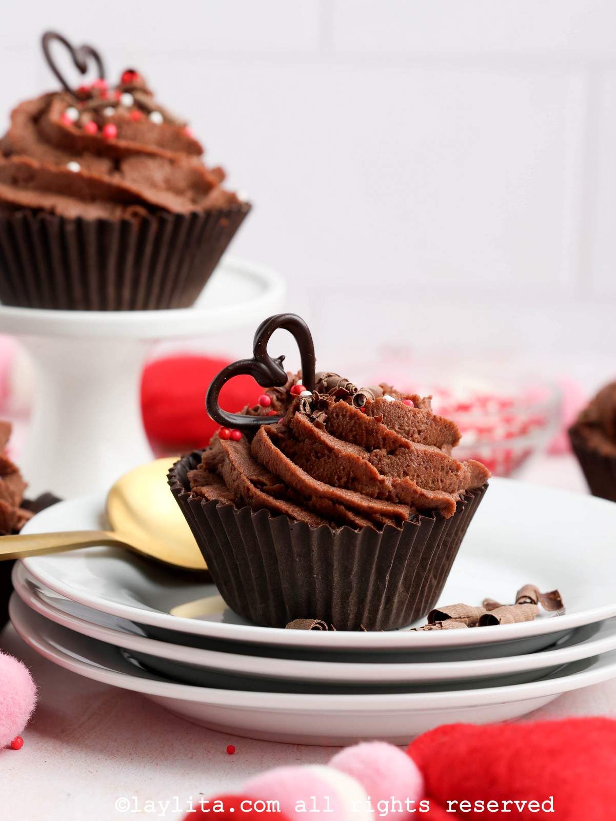 A chocolate mousse cup on top of three white plates, with another one in the background