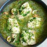 Overhead view of Spanish pescado en salsa verde in a large black skillet