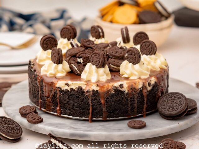 Oreo cheesecake on a marble slab topped with whipped cream and Oreo cookies.