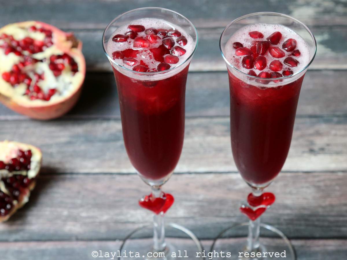 Two champagne glasses filled with a sparkling pomegranate tequila drink garnished with fresh pomegranate arils