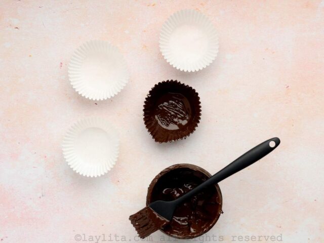 Paper cupcake liners being painted with melted chocolate