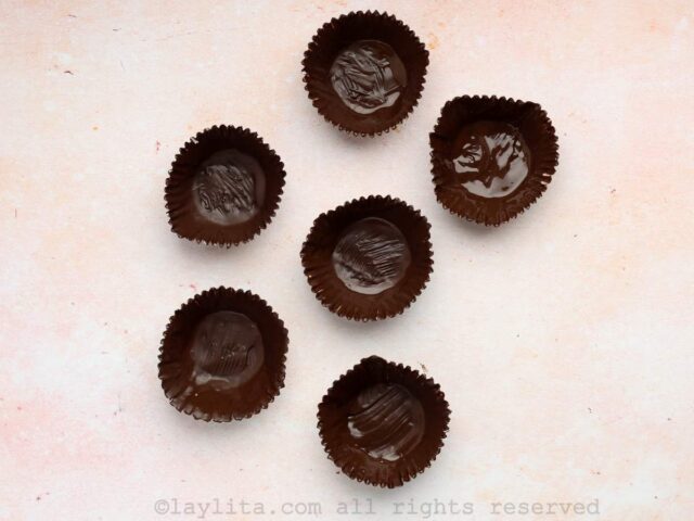 Six cupcake liners painted with melted chocolate on a kitchen counter