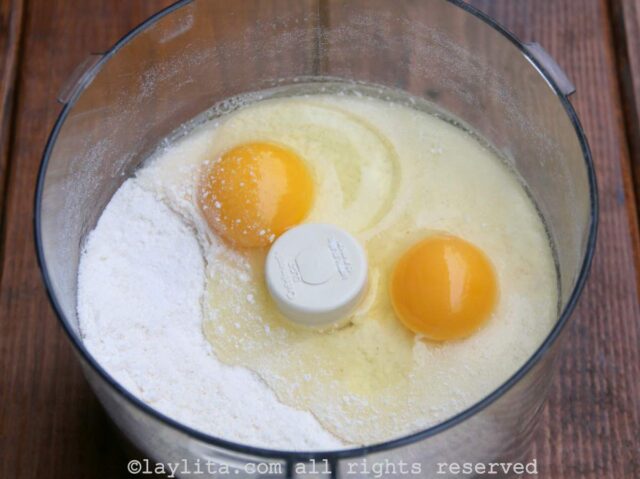 Two eggs being added to the flour mix in a food processor