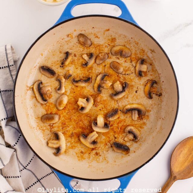 Mushroom slices cooking a blue pot