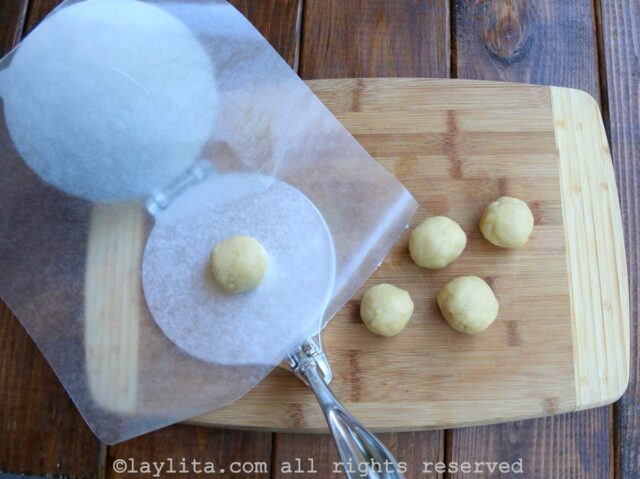 Balls of dough being pressed in a tortilla press