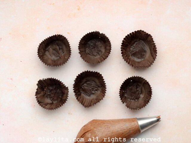 Edible chocolate cups next to a piping bag filled with chocolate mousse