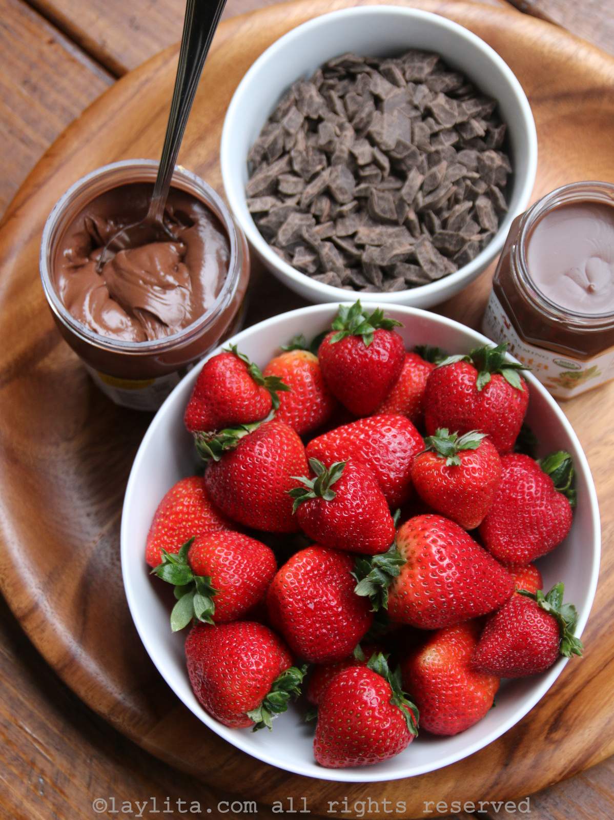 Ingredients needed to make the filling for homemade strawberry nutella empanadas on a wooden board.