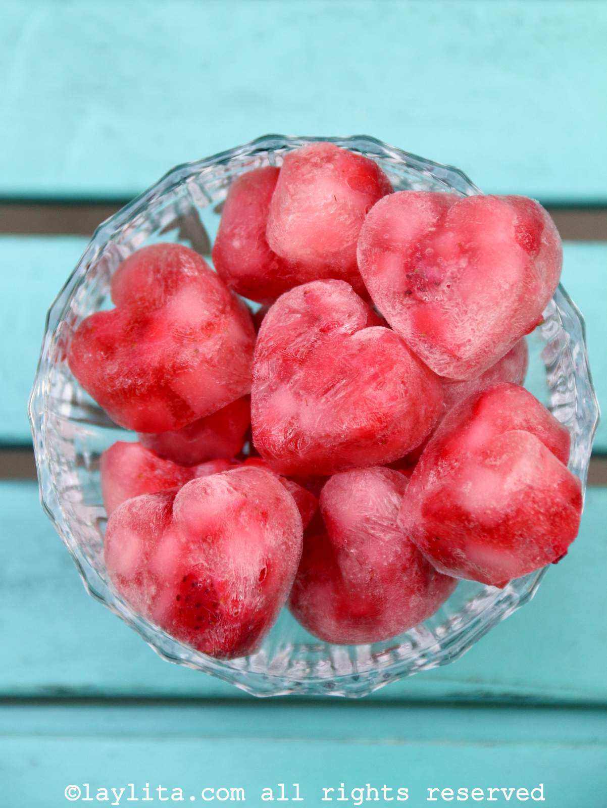 A glass bowl full of heart shaped ice cubes made from strawberries and champagne