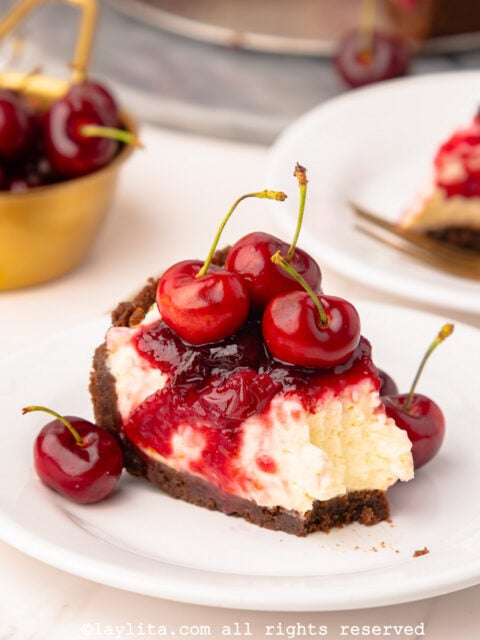 Slice of no bake cherry cheesecake on a plate with a forkful taken out of it