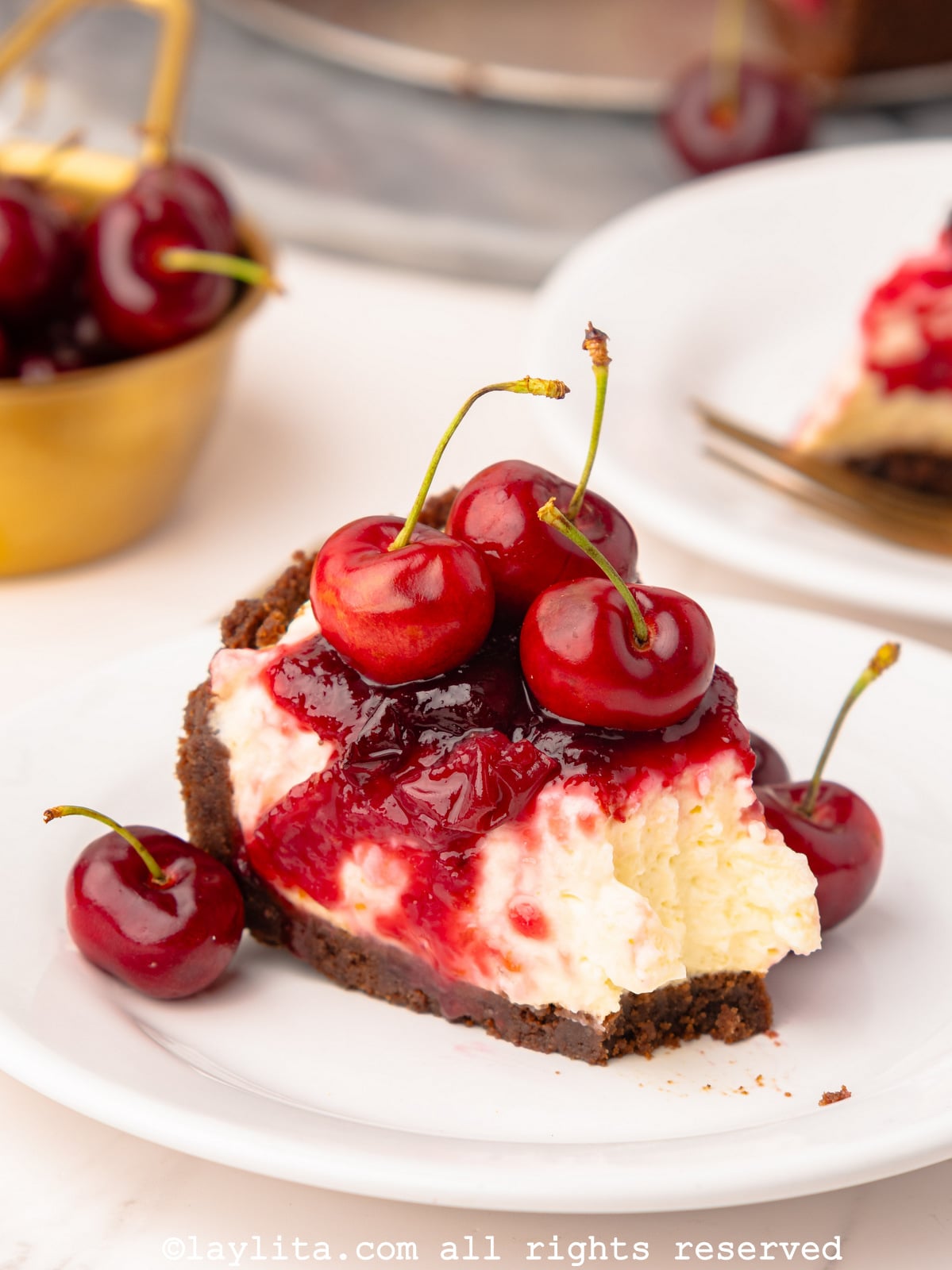 Slice of no bake cherry cheesecake on a plate with a forkful taken out of it