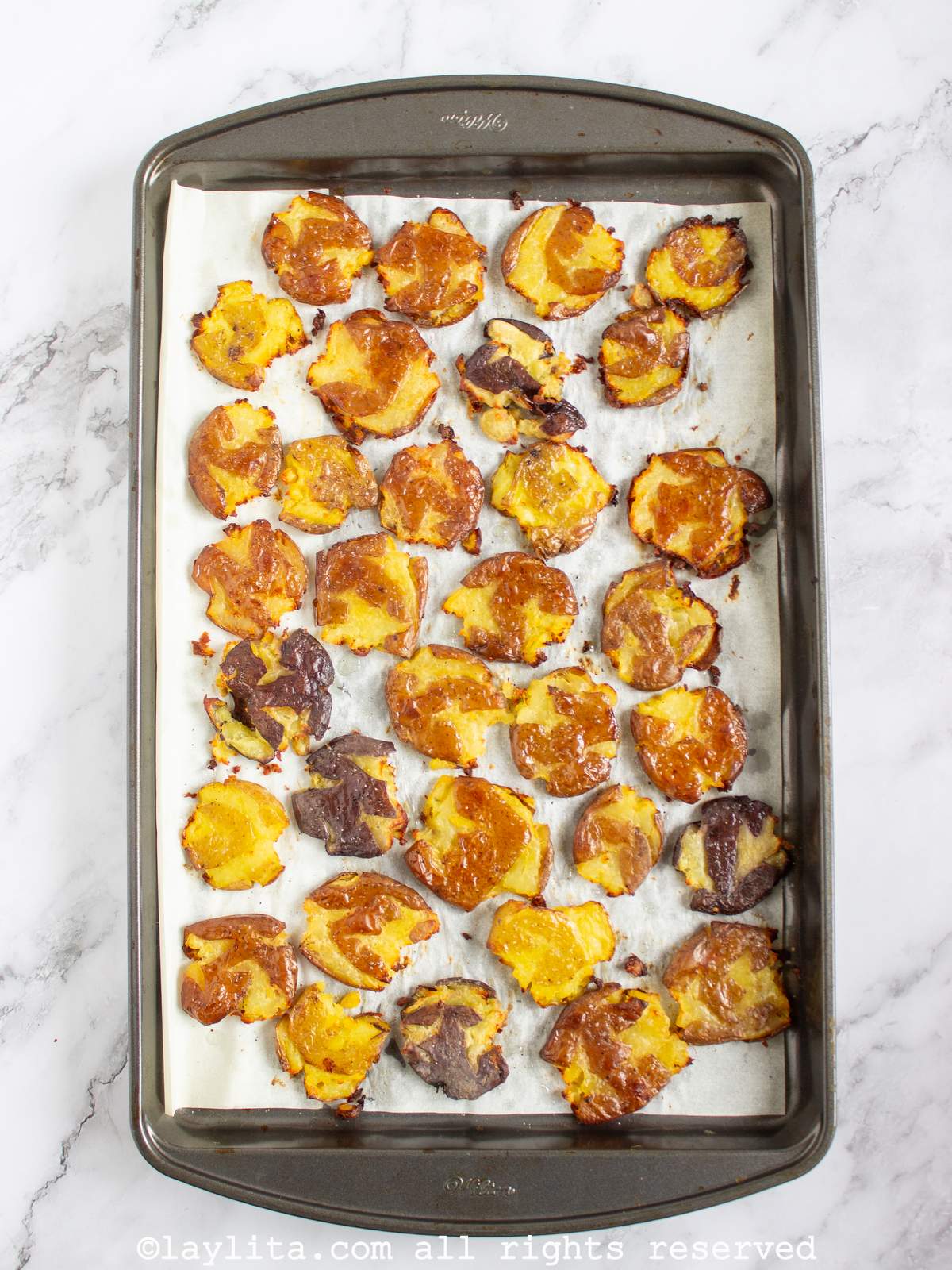 Overhead shot of a baking pan full of oven roasted smashed potatoes