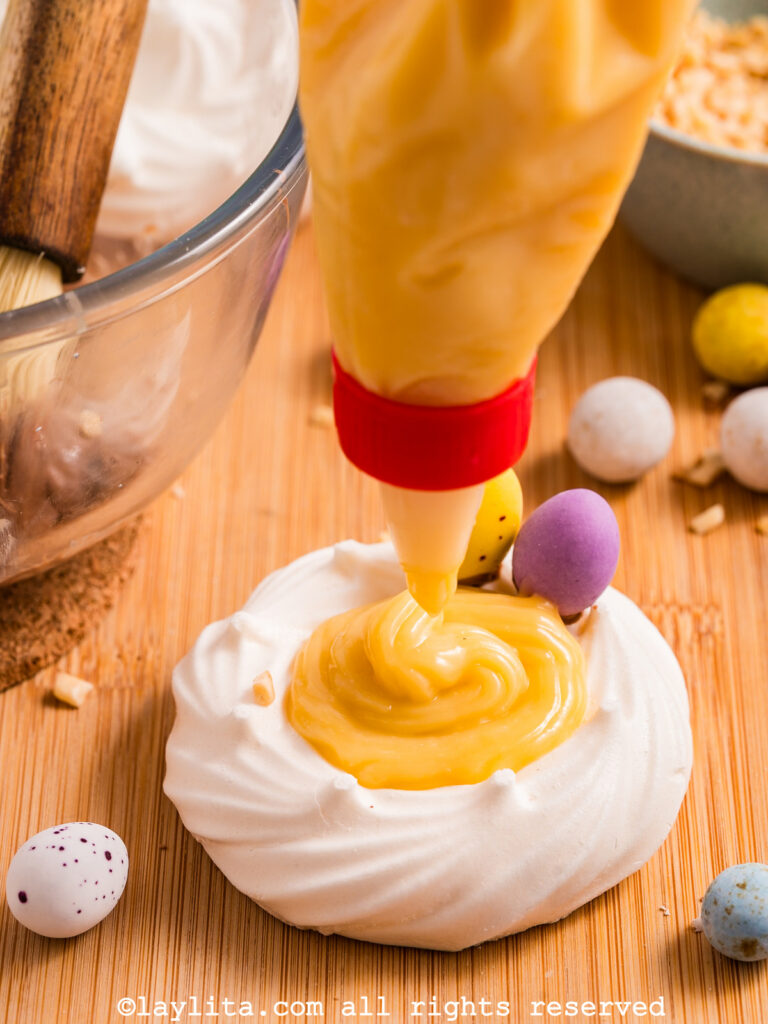 Lemon custard being added to a meringue nest