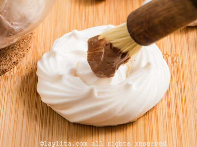 Brushing melted chocolate on to a meringue nest