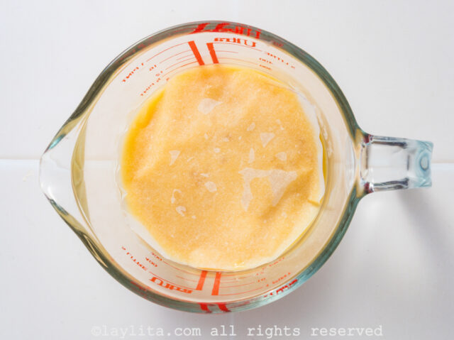 A glass container with lemon custard covered with plastic wrap