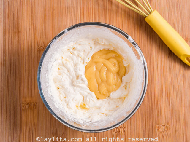 Whipped cream and lemon custard being mixed together in a bowl