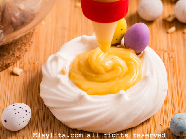 A meringue nest being filled with lemon custard