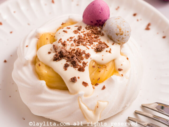 A meringue nest with lemon custard and cream on a white palte