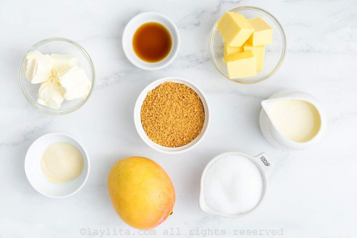 Ingredients needed to make mango cheesecake on a kitchen counter.
